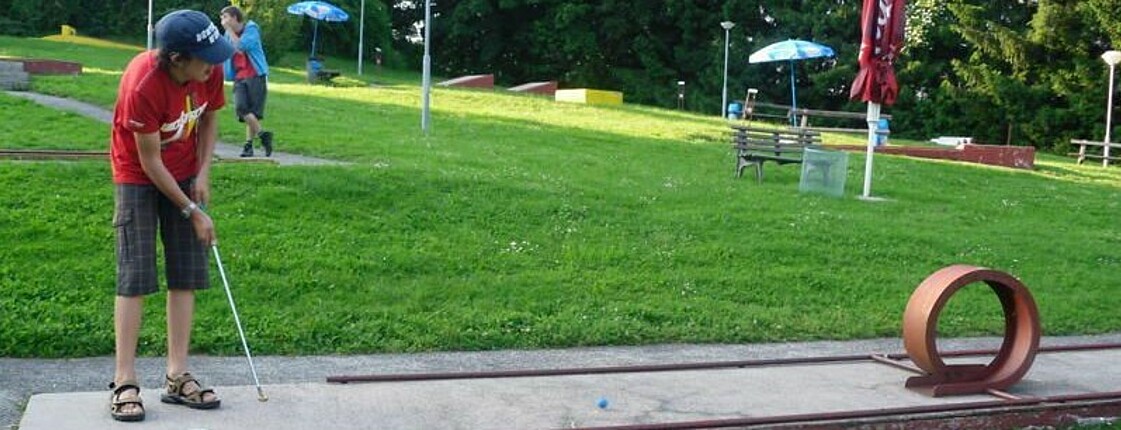 Ein Junge spielt Minigolf.